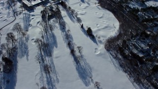 AX66_0020E - 4.8K aerial stock footage of a country road by bare trees in snow, reveal mansions, Old Westbury, New York