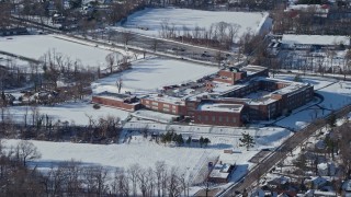 AX66_0035 - 4.8K aerial stock footage of orbiting a school in snow, Great Neck, New York