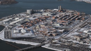AX66_0050 - 4.8K aerial stock footage of flying by prison buildings Rikers Island Prison in snow, New York