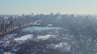 AX66_0100E - 4.8K aerial stock footage of a wide view of Central Park in snow and Midtown Manhattan skyscrapers, New York City