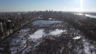 AX66_0102 - 4.8K stock footage aerial video fly over snowy Central Park toward Midtown, New York City
