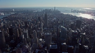 AX66_0110E - 4.8K aerial stock footage fly over Midtown's skyscrapers, approach the famous Empire State Building in snow, New York City