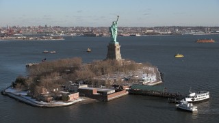 AX66_0128 - 4.8K aerial stock footage of an orbit of Statue of Liberty in snow on New York Harbor, New York