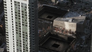 AX66_0139 - 4.8K aerial stock footage tilt to World Trade Center Memorial with snow, New York City