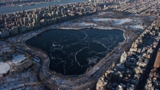 AX66_0191E - 4.8K aerial stock footage of Jacqueline Kennedy Onassis Reservoir in Central Park in snow, New York City