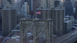 AX66_0235 - 4.8K stock footage aerial video orbit flag on top of the Brooklyn Bridge, New York City, at sunset