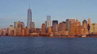 AX66_0260E - 4.8K aerial stock footage tilt from harbor to reveal Lower Manhattan skyline, New York City, sunset