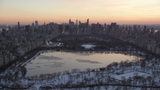 AX66_0297 - 4.8K stock footage aerial video of Central Park lake and Midtown Manhattan skyline in winter, New York City, twilight