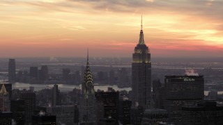 AX66_0313 - 4.8K stock footage aerial video orbiting Empire State Building and Chrysler Building in front of a beautiful winter sunset, New York City, twilight
