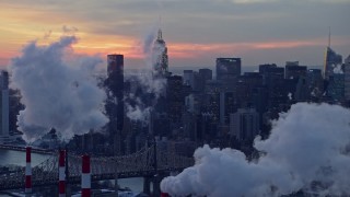 AX66_0317E - 4.8K aerial stock footage of Midtown Manhattan smoke stacks and skyscrapers in winter, New York City, twilight