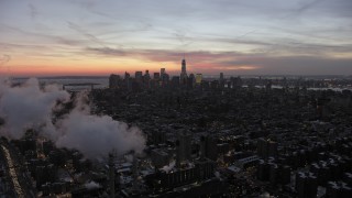 AX66_0356 - 4.8K aerial stock footage of Lower Manhattan behind smoke stacks in winter, New York City, twilight