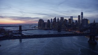 AX66_0363E - 4.8K aerial stock footage of Manhattan Bridge and Brooklyn Bridge on East River in winter, New York City, twilight