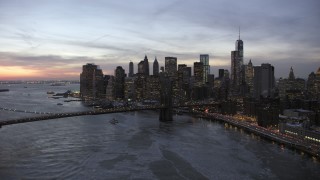 AX66_0365 - 4.8K aerial stock footage of Brooklyn Bridge and Lower Manhattan skyscrapers in winter, New York City, twilight