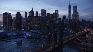 AX66_0366E - 4.8K aerial stock footage approach Brooklyn Bridge and Lower Manhattan skyscrapers in winter, New York City, twilight