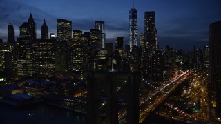 AX66_0404E - 4.8K aerial stock footage approach and orbit Brooklyn Bridge, reveal Lower Manhattan skyscrapers in winter, New York City, twilight