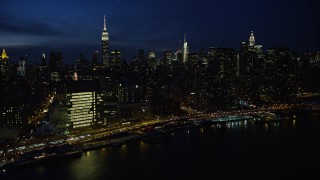 AX66_0415E - 4.8K aerial stock footage of passing Midtown Manhattan skyscrapers and United Nations building, New York City, night