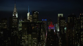 AX66_0443E - 4.8K aerial stock footage of Chrysler Building, city canyons and the Empire State Building in Midtown Manhattan, New York City, night