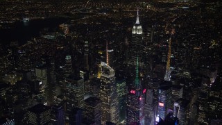 AX67_0041 - 4.8K aerial stock footage view orbit Bank of America Tower in Midtown Manhattan at night, reveal Empire State Building, New York