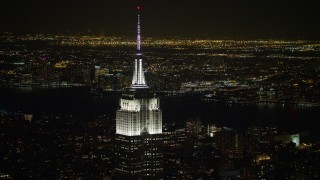 AX67_0046 - Aerial stock footage of 4.8K aerial video view of the Empire State Building with Hudson River in the background at night, Midtown Manhattan, New York City, New York