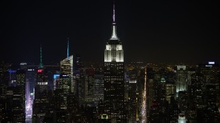 AX67_0049 - Aerial stock footage of 4.8K aerial video view of the Empire State Building and Midtown skyscrapers at night, Midtown Manhattan, New York City, New York