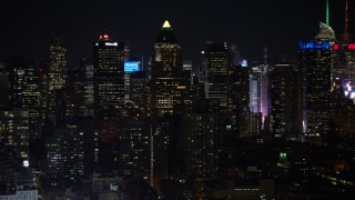 AX67_0058 - 4.8K aerial stock footage view of panning across and passing Midtown Manhattan skyscrapers at night, New York