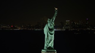 AX67_0074 - Aerial stock footage of 4.8K aerial  video of orbiting the back of the Statue of Liberty at night, reveal World Trade Center skyline, New York