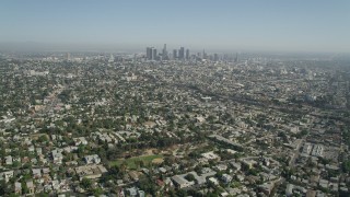 AX68_009 - 4.8K stock footage aerial video tilt from urban neighborhoods to reveal Downtown Los Angeles skyline, California