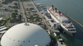 AX68_068 - 4.8K aerial stock footage reverse view of the Queen Mary luxury liner and reveal Downtown Long Beach, California