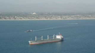 AX68_082 - 4.8K aerial stock footage of a barge sailing near an oil tanker in San Pedro Bay near the coast, Long Beach, California