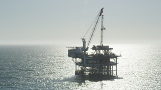 AX68_093 - 4.8K aerial stock footage of circling an oceanic oil platform near Long Beach, California
