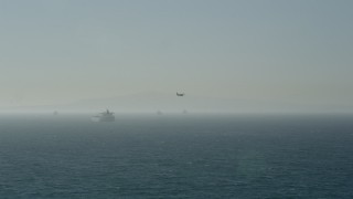 AX68_114 - 4.8K aerial stock footage of tracking a seaplane flying by oil tankers near San Pedro Bay, Long Beach, California