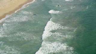 AX68_120 - 4.8K aerial stock footage reverse view of a kite surfer in San Pedro Bay by the beach, Long Beach, California