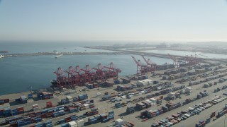 AX68_143 - 4.8K stock footage aerial video of cargo ships under cranes near containers at the Port of Long Beach, California