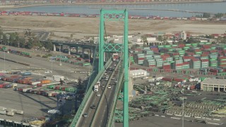 AX68_152 - 4.8K aerial stock footage of traffic on the Vincent Thomas Bridge near Port of Los Angeles shipping containers, California
