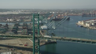 AX68_164 - 4.8K aerial stock footage fly over Vincent Thomas Bridge to approach cranes at the Port of Los Angeles, California