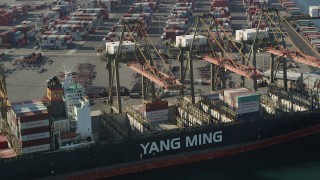 AX68_168 - 4.8K aerial stock footage of cranes working over a cargo ship at the Port of Los Angeles, California