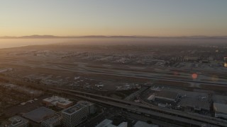AX69_005 - 4.8K aerial stock footage of sunset at LAX with an airliner on a runway in Los Angeles, California