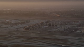 AX69_006 - 4.8K aerial stock footage of terminals, hangars and airliners at LAX at sunset, Los Angeles, California