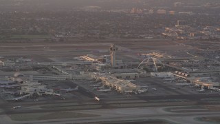 AX69_008 - 4.8K aerial stock footage of LAX control tower and terminals as airliner lands at sunset, Los Angeles, California