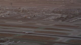 AX69_012 - 4.8K aerial stock footage track airliner on runway and tilt to reveal control tower and terminals at LAX at twilight, Los Angeles, California
