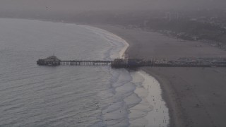 AX69_028 - 4.8K aerial stock footage of Santa Monica Pier at sunset and people walking the beach, California