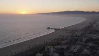 AX69_030 - 4.8K aerial stock footage of the Santa Monica Pier with the sun setting in the horizon, California