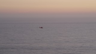 AX69_044 - 4.8K aerial stock footage track a Coast Guard helicopter flying over the Pacific Ocean at twilight