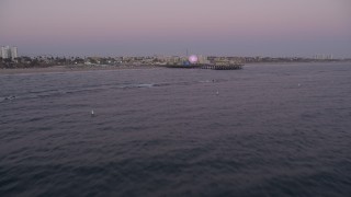 AX69_046 - 4.8K stock footage aerial video tilt from the ocean to reveal and approach Santa Monica Pier at twilight, California