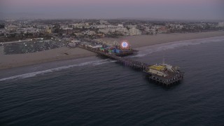 AX69_047 - 4.8K aerial stock footage approach Santa Monica Pier at twilight and tilt to a bird's eye view, California