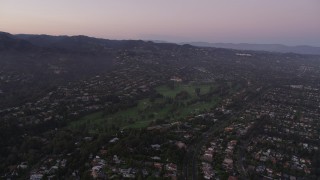 AX69_048 - 4.8K aerial stock footage approach a golf course and mansions at sunset in Pacific Palisades, California