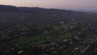 AX69_049 - 4.8K aerial stock footage tilt to golf course ringed by mansions at twilight in Pacific Palisades, California