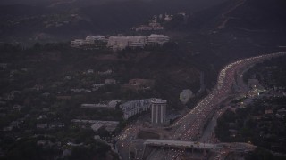 AX69_054 - 4.8K stock footage aerial video of J. Paul Getty Museum, Hotel Angeleno, and I-405 with heavy traffic at twilight, Brentwood, California