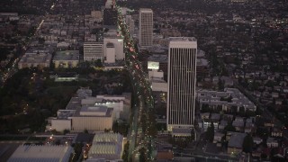 AX69_072 - 4.8K aerial stock footage tilt from Wilshire Boulevard in Beverly Hills to reveal Downtown Los Angeles Skyline at twilight, California