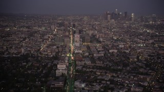 AX69_075 - 4.8K aerial stock footage tilt from Wilshire Boulevard to reveal Koreatown and Downtown LA skyline at night, California